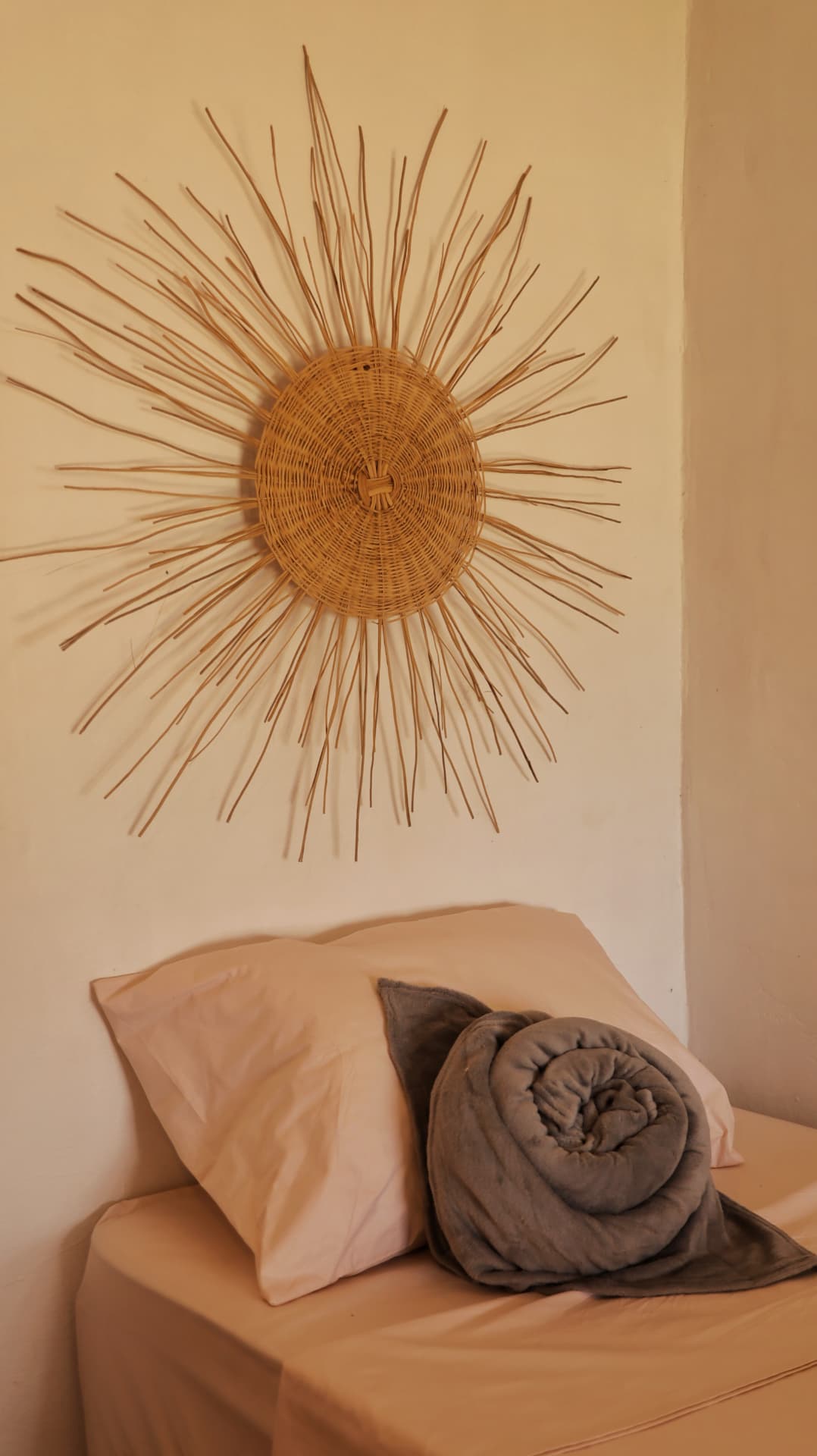 Cama com sol decorativo de palha na parede