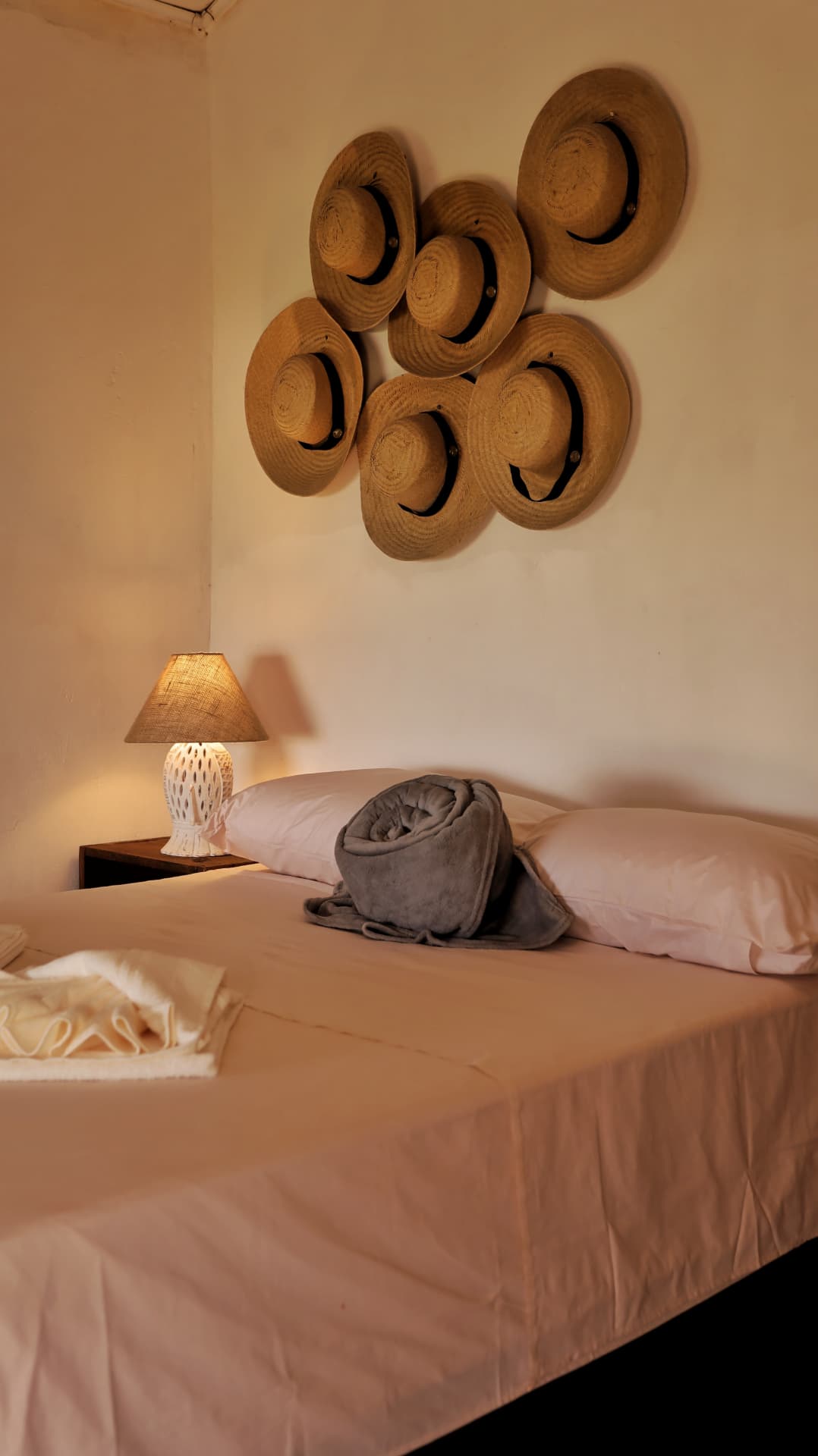 Cama de casal com chapéus de palha na parede