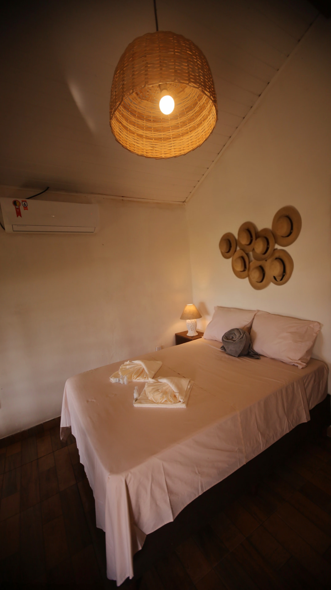 Quarto com ar-condicionado e luminária de palha