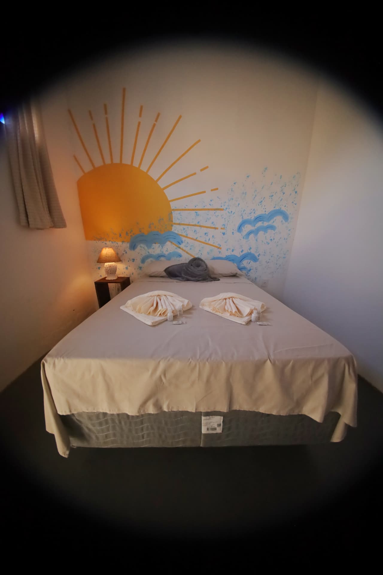 Cama de casal com painel de sol e ondas pintado na parede
